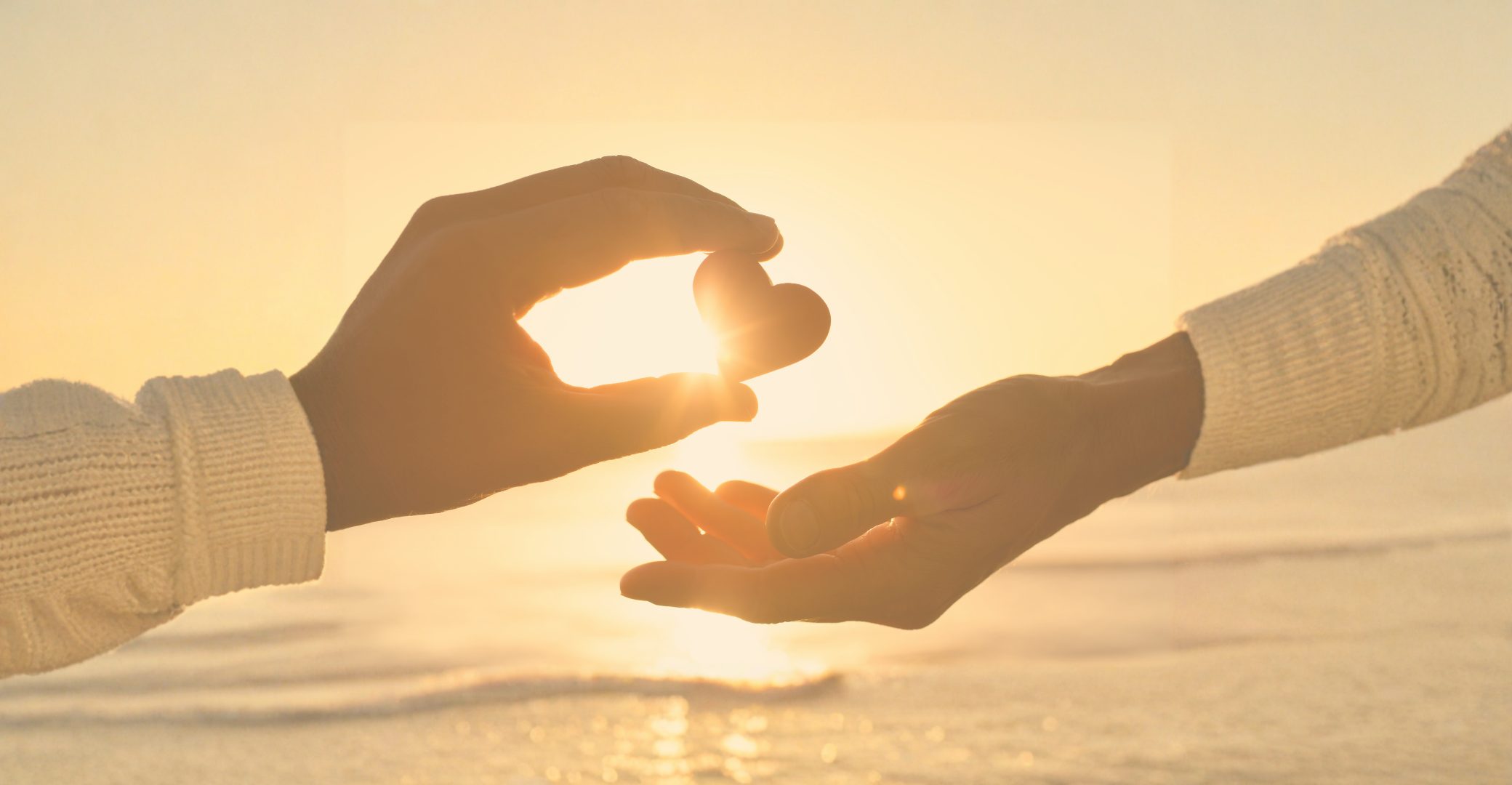 Header photo shows helping hands reaching out to give a heart to another person.