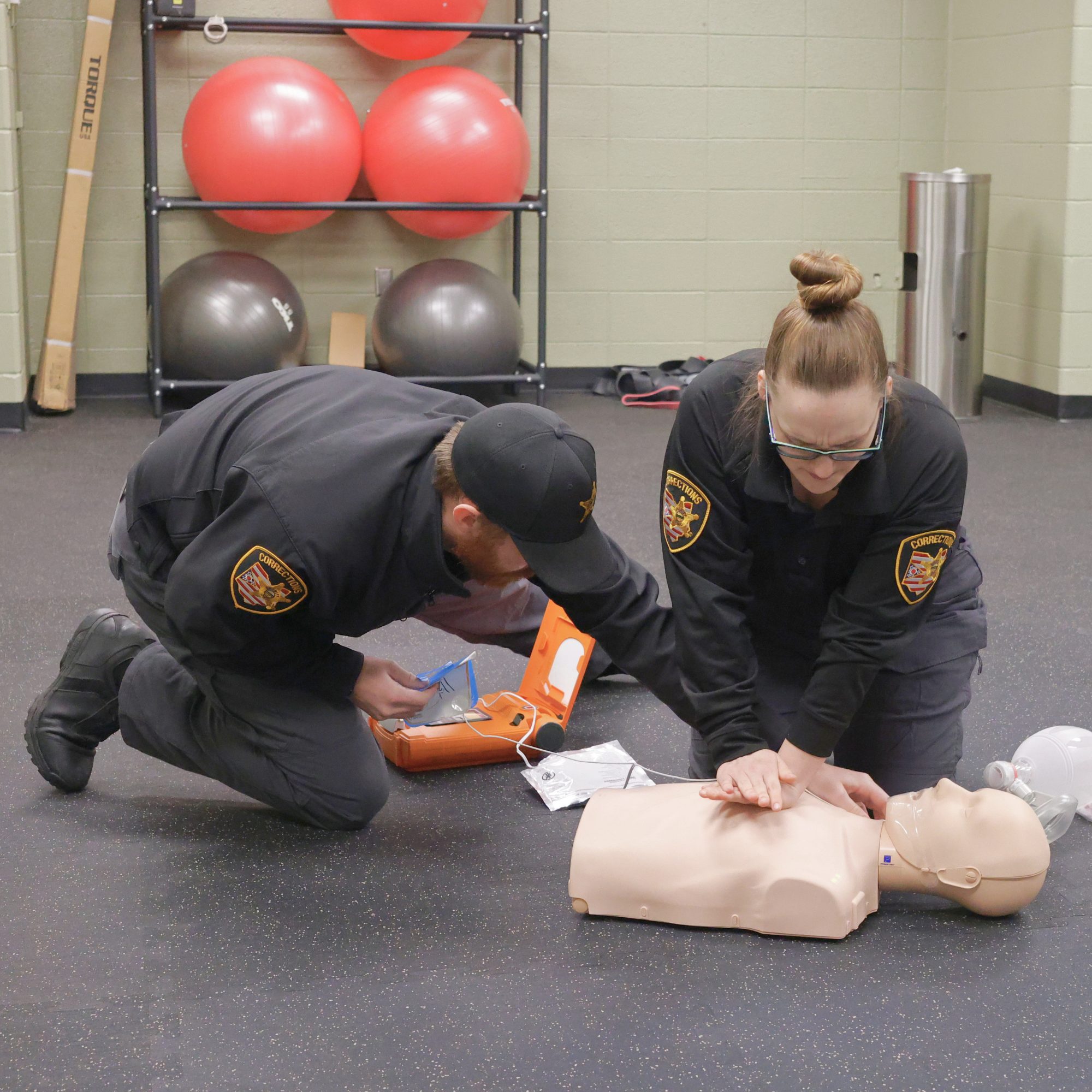 Two officers practicing CPR on a training mannequin.